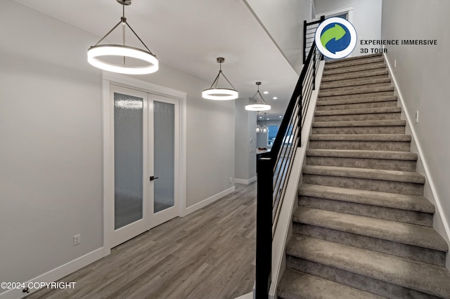 staircase with french doors and hardwood / wood-style floors