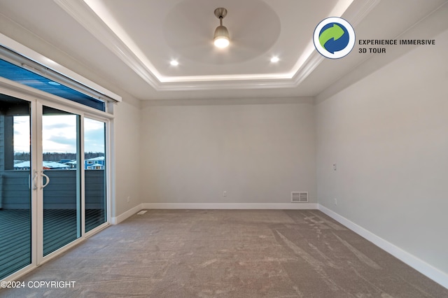 carpeted empty room featuring ceiling fan, crown molding, and a tray ceiling