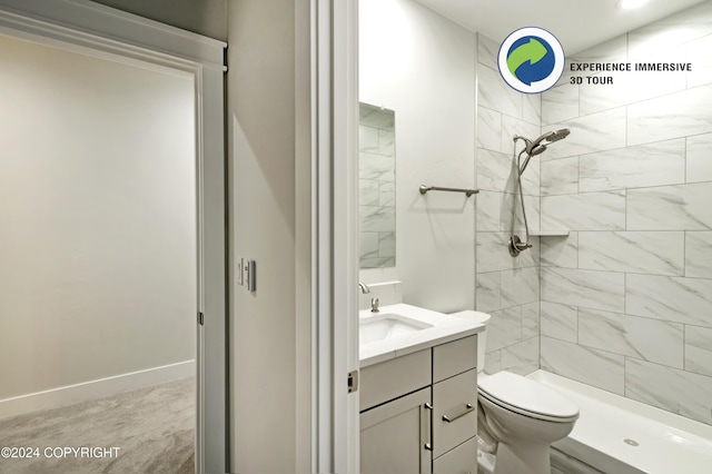 bathroom featuring vanity, toilet, and a tile shower