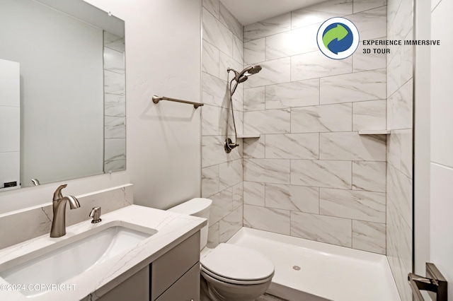 bathroom featuring toilet, vanity, and tiled shower