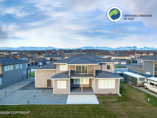 rear view of property featuring a mountain view, a lawn, and a balcony