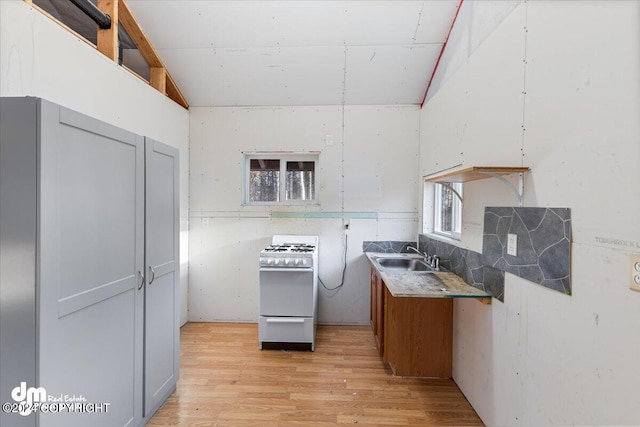 kitchen with sink, white gas stove, light hardwood / wood-style flooring, and gray cabinets