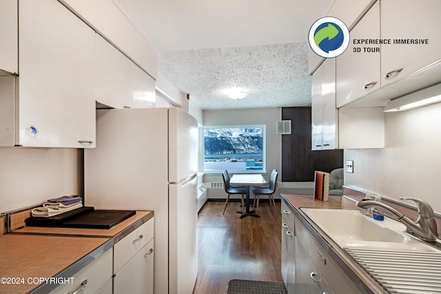 kitchen with a textured ceiling, white cabinetry, and dark wood-type flooring