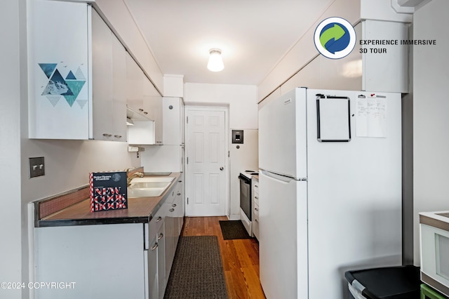 kitchen featuring sink, stainless steel range oven, white fridge, dark hardwood / wood-style flooring, and white cabinetry