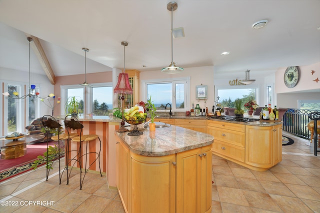 kitchen featuring a kitchen island, light stone countertops, vaulted ceiling with beams, and plenty of natural light