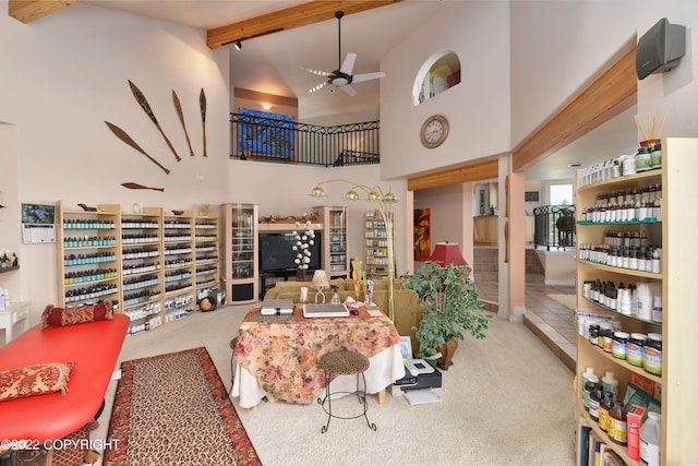 carpeted living room with beam ceiling, high vaulted ceiling, and ceiling fan