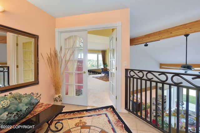 entryway with french doors, beam ceiling, and light colored carpet