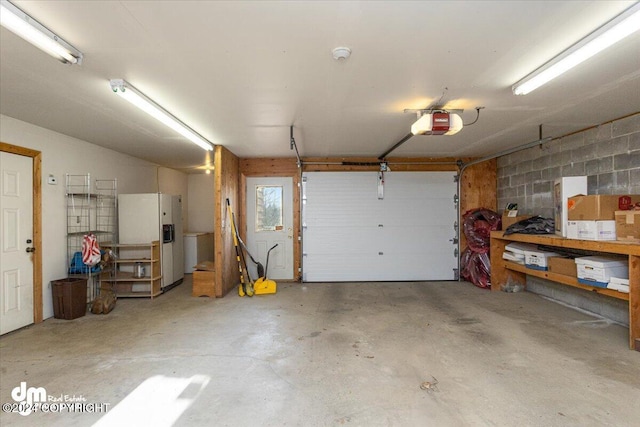 garage featuring a garage door opener and white refrigerator with ice dispenser