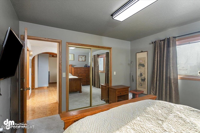 bedroom featuring parquet flooring, a textured ceiling, and a closet