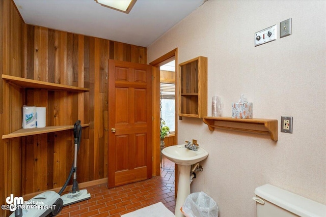 bathroom with wood walls and toilet