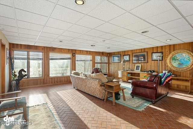 living room with wood walls and a drop ceiling