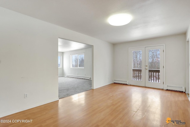 empty room featuring a baseboard radiator, french doors, and light wood-type flooring