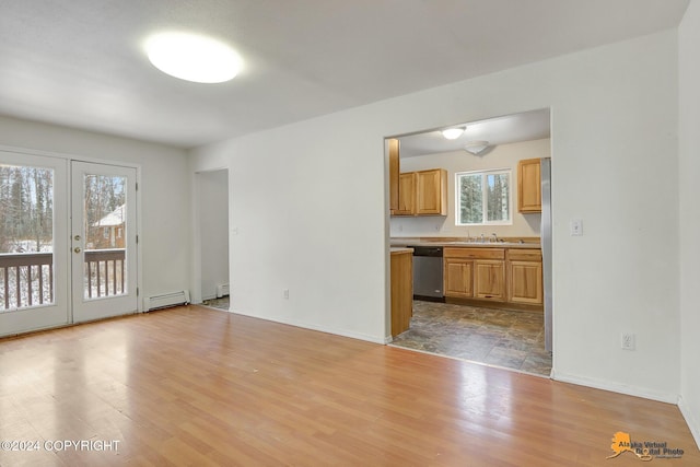 unfurnished living room featuring a baseboard radiator, french doors, light wood-type flooring, and sink