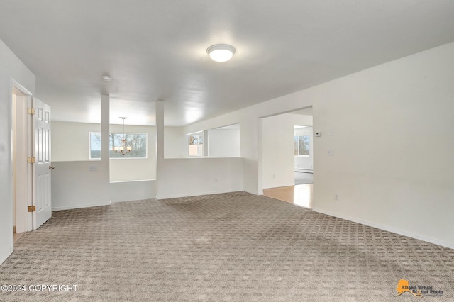 carpeted spare room featuring a notable chandelier