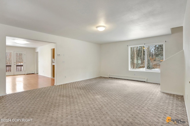 empty room with a baseboard heating unit, light carpet, and a healthy amount of sunlight