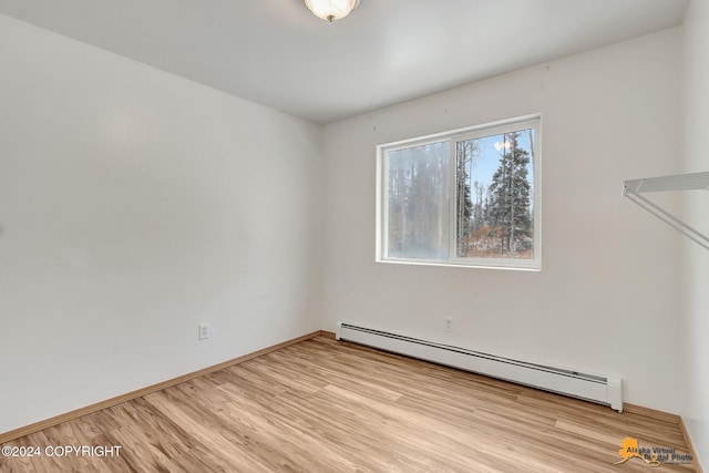 spare room featuring a baseboard radiator and light wood-type flooring