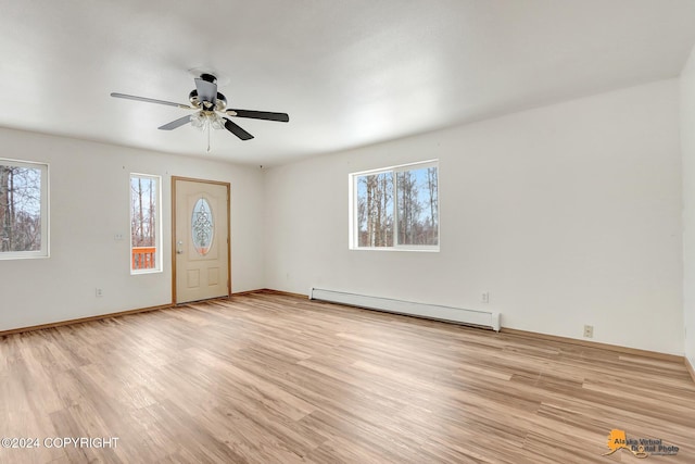 empty room with light hardwood / wood-style floors, baseboard heating, and ceiling fan