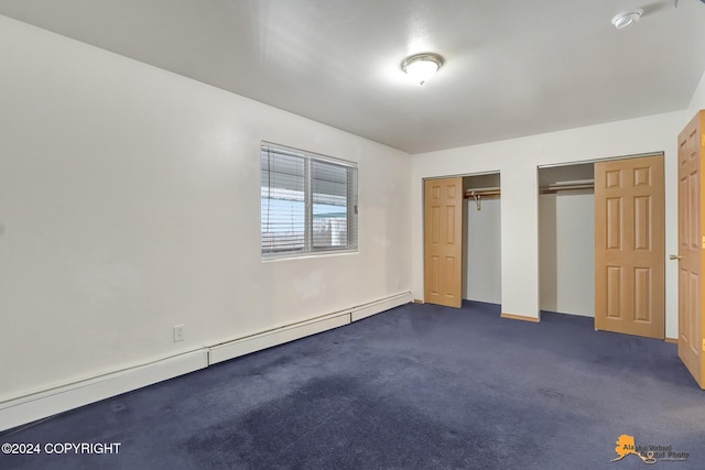 unfurnished bedroom with a baseboard heating unit, two closets, and dark colored carpet