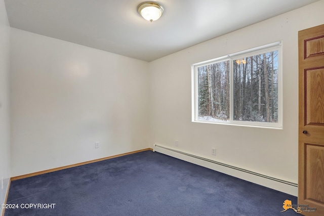 spare room featuring a baseboard heating unit, plenty of natural light, and dark colored carpet