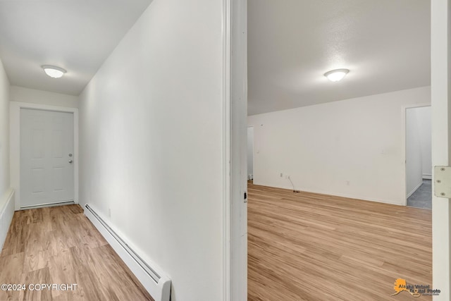 corridor with a baseboard heating unit and light wood-type flooring