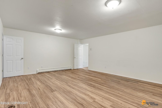 spare room featuring a baseboard radiator, a textured ceiling, and light wood-type flooring