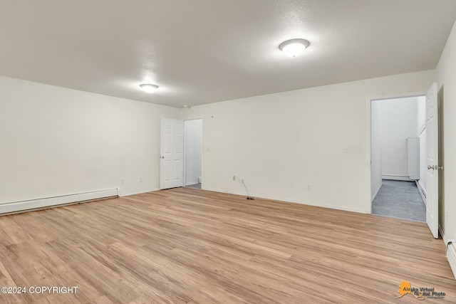 empty room featuring a textured ceiling, a baseboard radiator, and light wood-type flooring