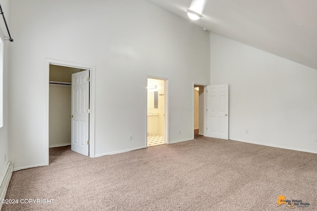 unfurnished bedroom featuring connected bathroom, a closet, a spacious closet, carpet floors, and high vaulted ceiling