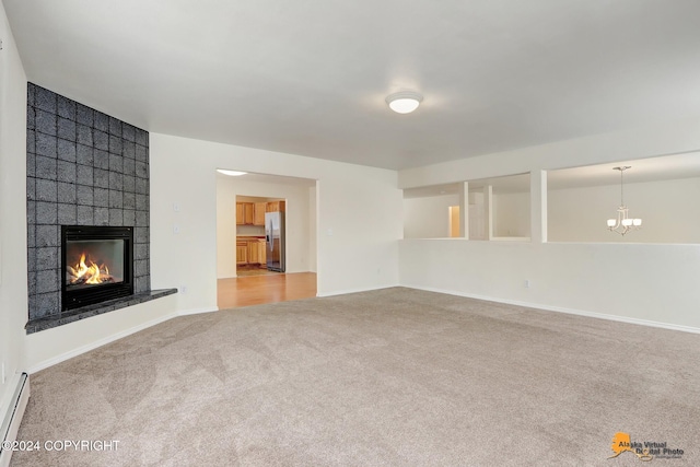 unfurnished living room with light carpet, a baseboard heating unit, and a fireplace