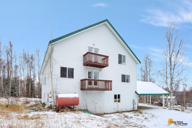 snow covered back of property with a balcony