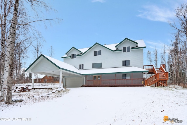 snow covered house with a carport and a deck