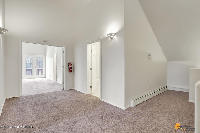 interior space with vaulted ceiling, a baseboard heating unit, and french doors