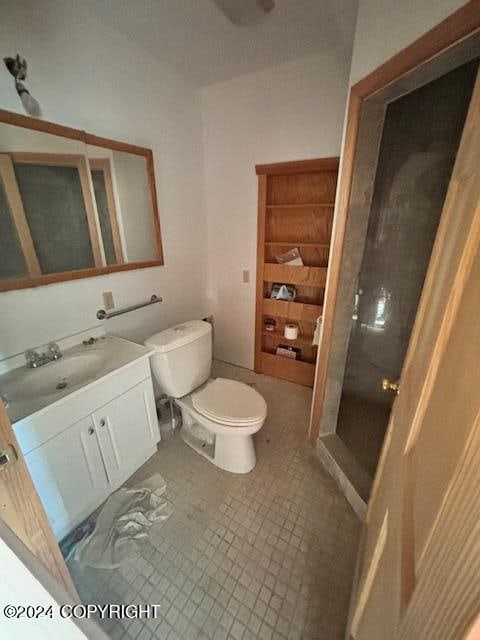 bathroom featuring toilet, walk in shower, vanity, and tile patterned flooring