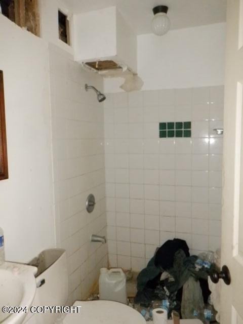 bathroom featuring toilet and a tile shower