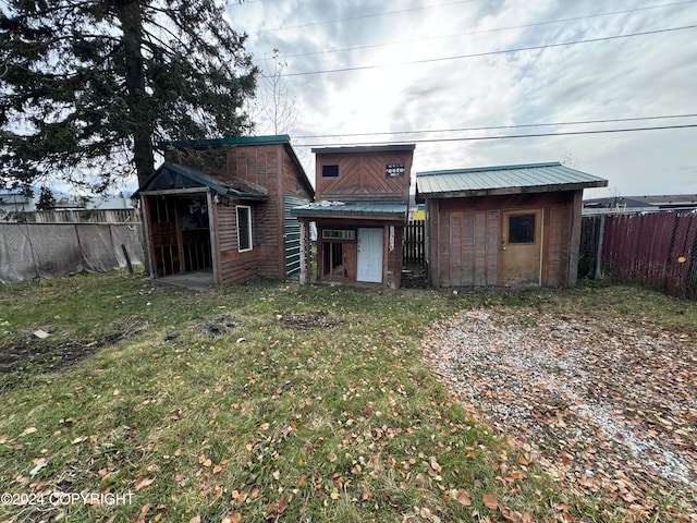 rear view of property with a shed and a lawn