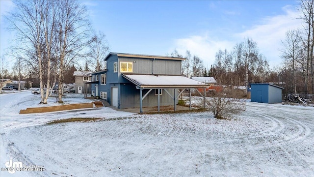 snow covered rear of property featuring a shed