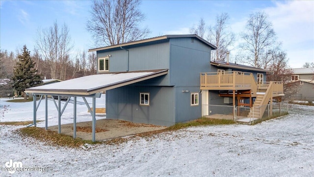 snow covered house with a wooden deck and a carport