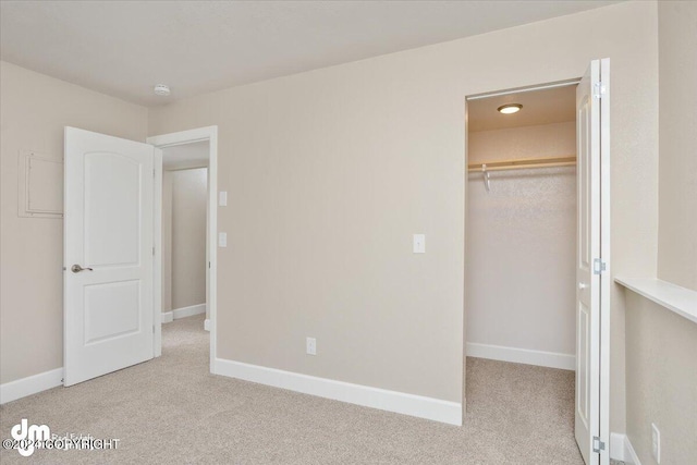 unfurnished bedroom with a spacious closet, light carpet, and a closet