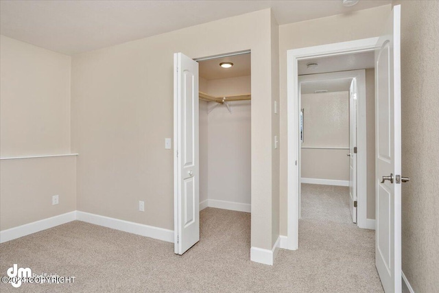 unfurnished bedroom featuring light carpet, a walk in closet, and a closet