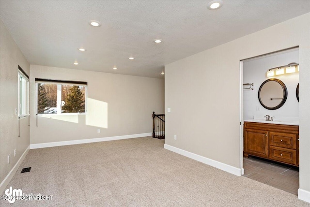 carpeted spare room featuring a textured ceiling and sink