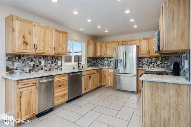 kitchen with stainless steel appliances, backsplash, sink, light brown cabinetry, and light stone counters