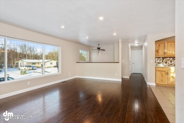 unfurnished living room featuring dark wood-type flooring and ceiling fan