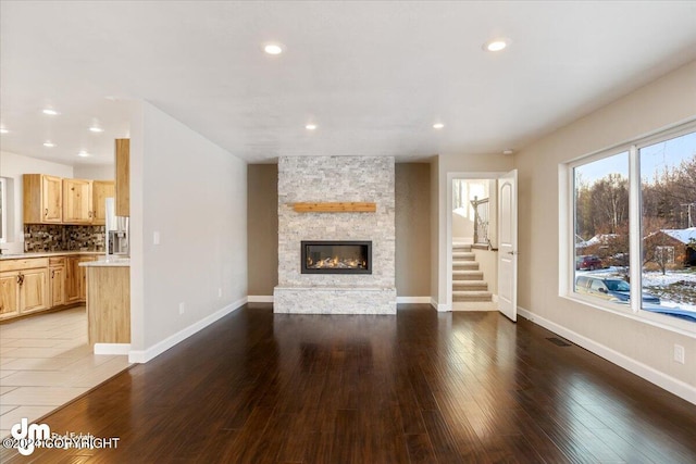 unfurnished living room with hardwood / wood-style floors and a stone fireplace