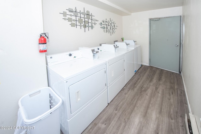 clothes washing area with washing machine and dryer and light hardwood / wood-style flooring