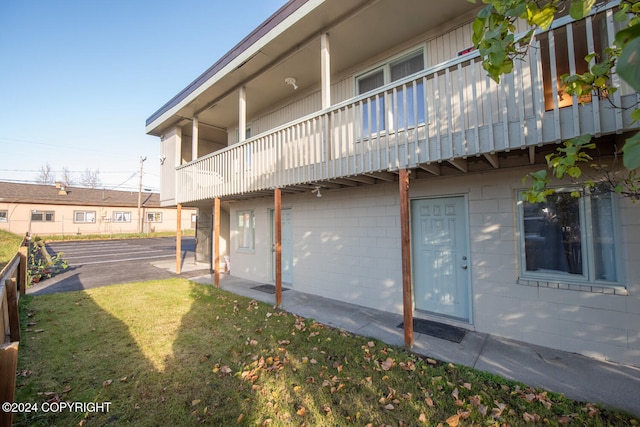 rear view of property featuring a patio, a balcony, and a yard