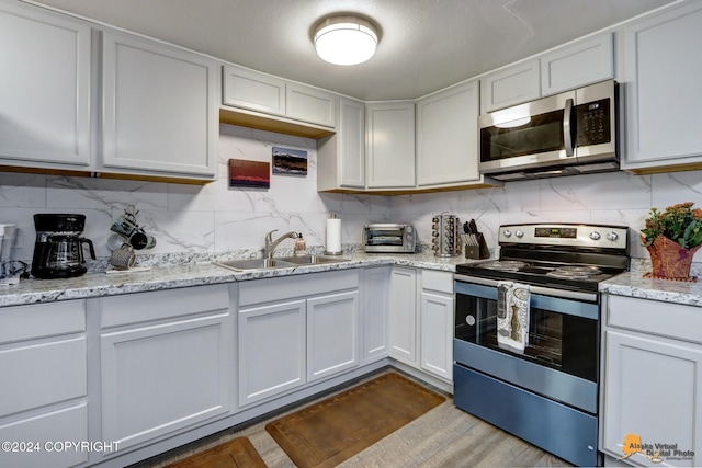 kitchen featuring white cabinetry, decorative backsplash, stainless steel appliances, and sink