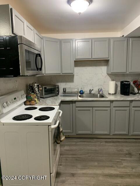 kitchen featuring white electric stove, gray cabinetry, sink, and hardwood / wood-style floors