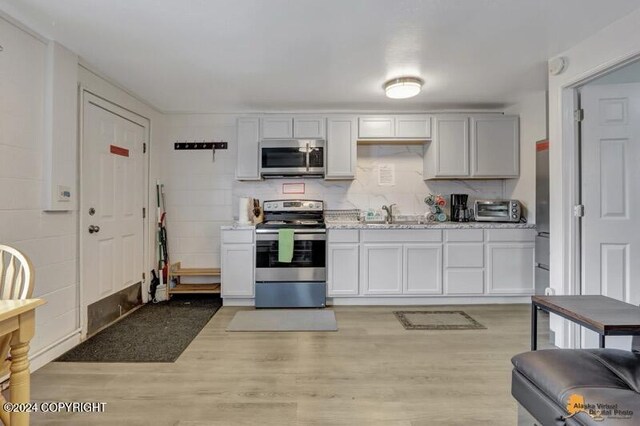 kitchen with light hardwood / wood-style floors, sink, appliances with stainless steel finishes, and tasteful backsplash