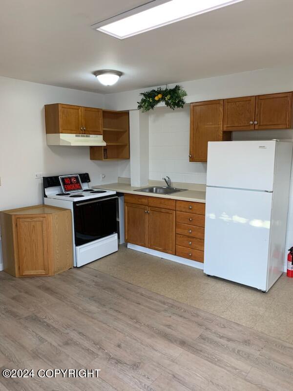 kitchen with white appliances, sink, and light hardwood / wood-style flooring