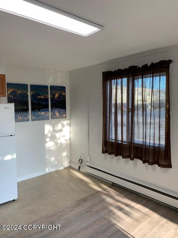 spare room with a baseboard heating unit and light wood-type flooring