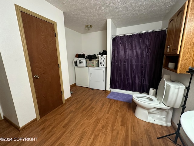 bathroom featuring toilet, wood-type flooring, washer and clothes dryer, and a textured ceiling